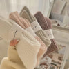 Set of four pairs of socks in beige, brown, and pink held together with a white band.