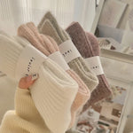Set of four pairs of socks in beige, brown, and pink held together with a white band.